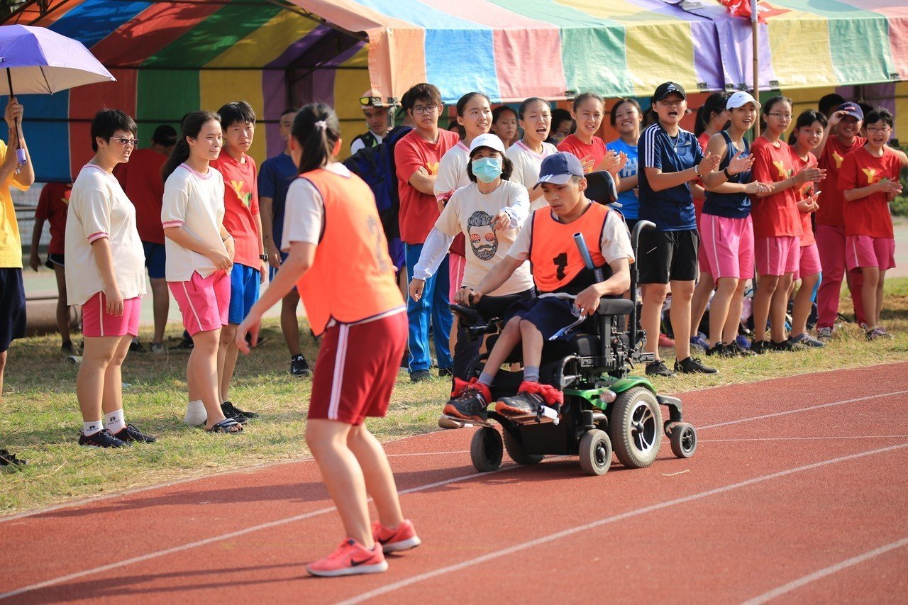 台南永仁高中三年級陳俊仲，以輪椅完成第一棒任務接棒給同學（圖：永仁高中）